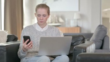 Dizüstü bilgisayarda çalışan Ciddi Kadın ve Evde Smartphone 
