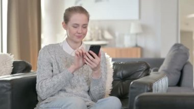 Evde akıllı telefon kullanan güzel bir genç kadın. 