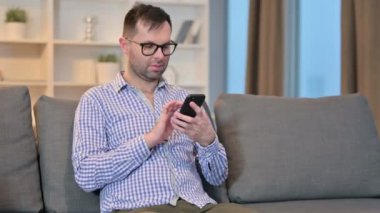 Evde akıllı telefon kullanan çekici genç adam. 