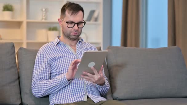 Seriös ung man som använder Tablet hemma — Stockvideo