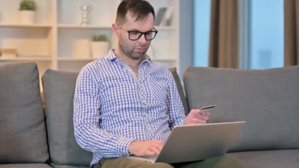 Emocionado joven haciendo el pago en línea en el ordenador portátil en casa — Vídeo de stock