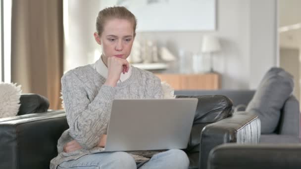 Jonge vrouw denken en werken op laptop thuis — Stockvideo