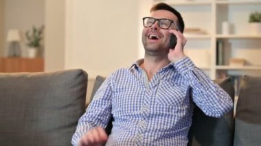 Genç adam evde akıllı telefondan konuşuyor. 
