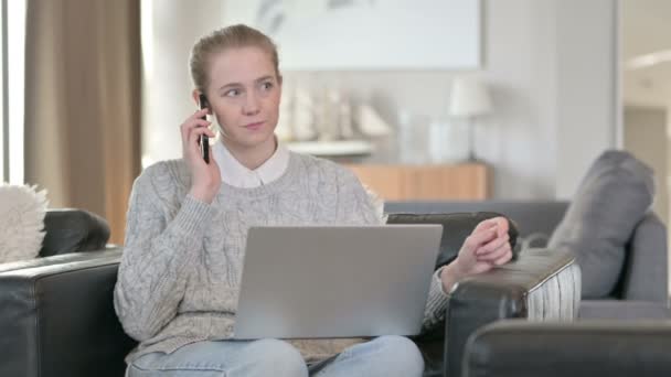 Glada kvinna med bärbar dator Prata på smartphone hemma — Stockvideo