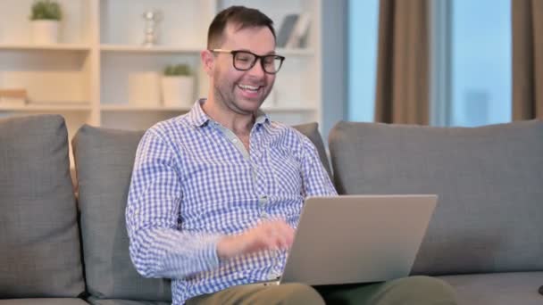 Homem animado fazendo chamada de vídeo no laptop em casa — Vídeo de Stock