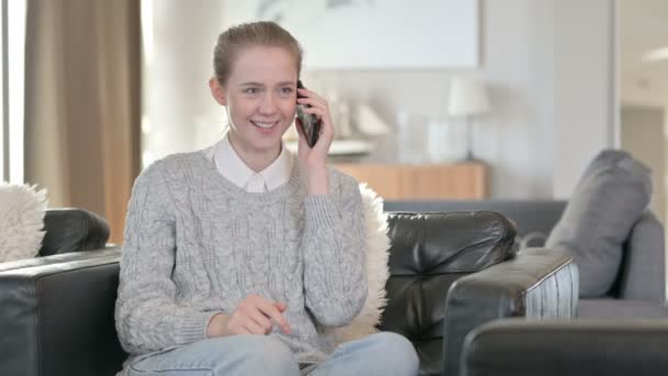 즐거운 젊은 여자가 집에서 스마트 폰으로 이야기하는 모습 — 비디오