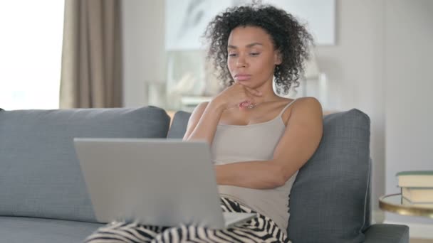 Pensive Afrikaanse vrouw denken en werken op laptop thuis — Stockvideo