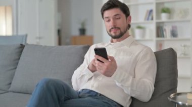 Evde akıllı telefon kullanan çekici genç iş adamı. 