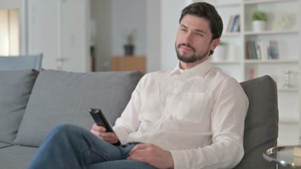 Attraente giovane imprenditore guardando la televisione a casa — Video Stock