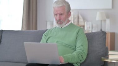 Dizüstü bilgisayarı olan yaşlı iş adamı evde boyun ağrısı çekiyor. 