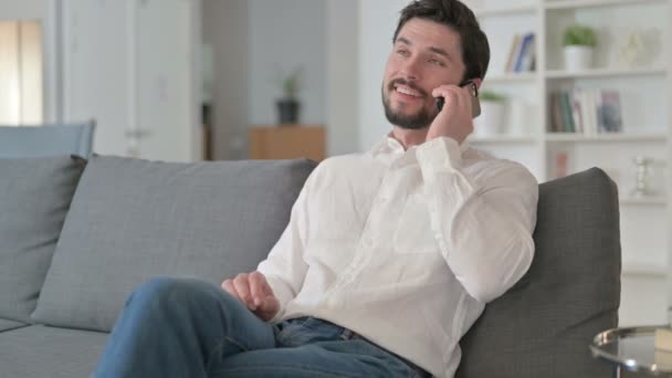 Joven empresario alegre hablando por teléfono inteligente en casa — Vídeos de Stock