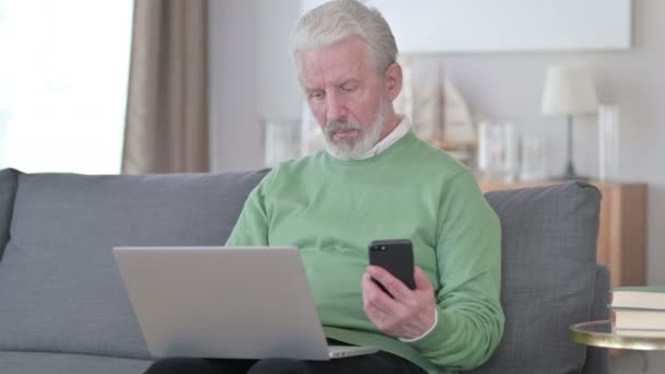 Привлекательный пожилой бизнесмен, работающий над смартфоном и ноутбуком — стоковое видео
