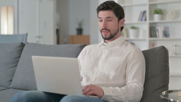 Веселый молодой бизнесмен делает видео-чат на ноутбуке дома — стоковое видео
