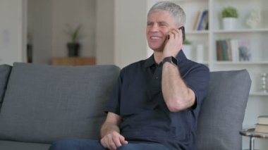 Neşeli Orta Çağ İşadamı Kanepede Smartphone 'da konuşuyor 