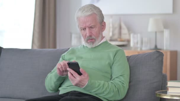 Sorglig äldre affärsman som har misslyckats med Smartphone hemma — Stockvideo