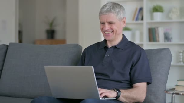 Hombre de negocios de mediana edad haciendo chat de vídeo en el ordenador portátil en el sofá — Vídeos de Stock