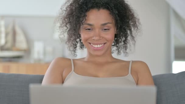 Mujer africana pensando y trabajando en el ordenador portátil — Vídeo de stock