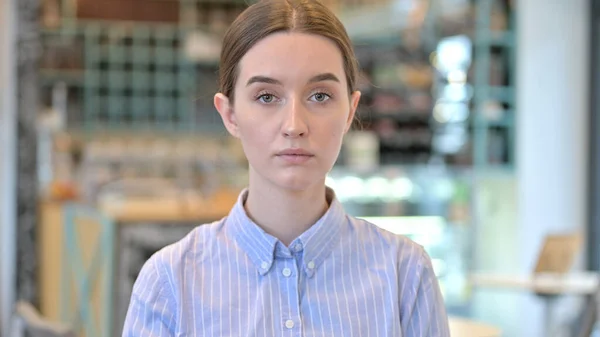 Portrait of Serious Young Woman Looking at Camera