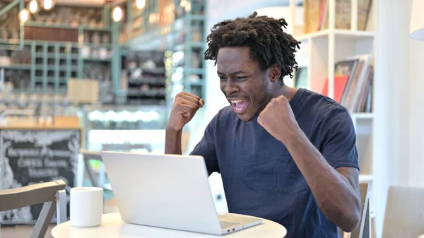 Úspěšný africký muž slaví na notebooku v kavárně — Stock fotografie