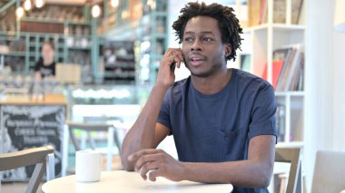 Cafe 'de akıllı telefondan konuşan Afrikalı adam.