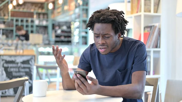 Homem Africano Reagindo à Perda no Smartphone no Café — Fotografia de Stock