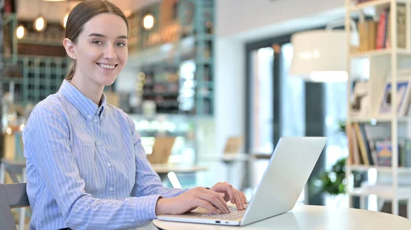 Laptop uso por mulher jovem sorrindo para a câmera no café — Fotografia de Stock