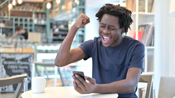 Překvapený Afričan při pohledu na Smartphone v Cafe — Stock fotografie