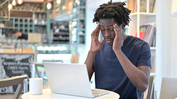 Afrikanischer Mann mit Kopfschmerzen arbeitet im Café am Laptop — Stockfoto