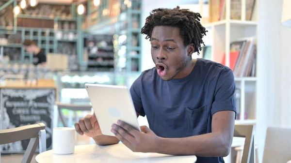 African Man Celebrating on Tablet in Cafe, Success