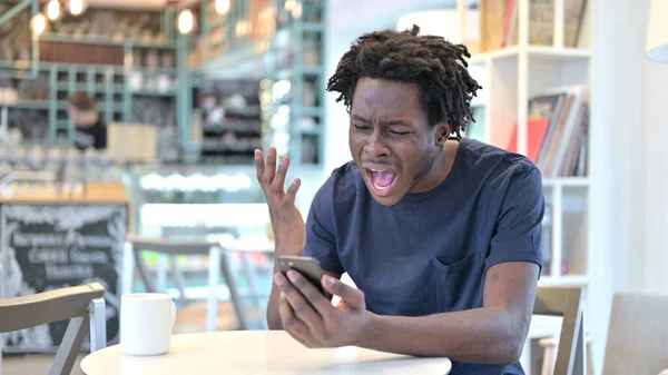 Gritando homem africano perturbado por falha no smartphone no café — Fotografia de Stock