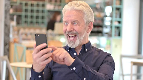 Porträt eines alten Mannes begeistert über Ergebnisse auf Smartphone — Stockfoto