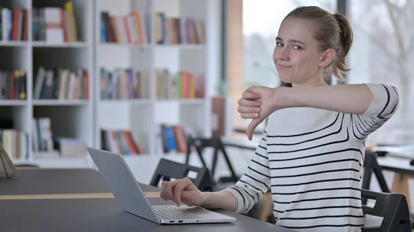 Duimen omlaag door jonge vrouw met behulp van laptop in de bibliotheek — Stockfoto