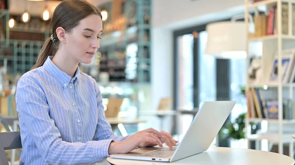 Atraktivní mladá žena pracující na notebooku v kavárně — Stock fotografie