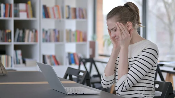 Laptop używać przez młodą kobietę z bólem głowy w bibliotece — Zdjęcie stockowe
