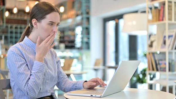 Mladá žena v šoku při pohledu na notebook v kavárně — Stock fotografie