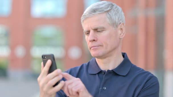 Ritratto all'aperto di uomo di mezza età ottenere scioccato su Smartphone — Video Stock