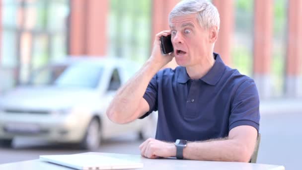 Hombre de negocios de mediana edad enojado al aire libre gritando en el teléfono inteligente — Vídeo de stock