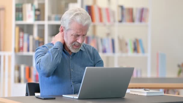 Starší starý muž s notebookem s bolestí v krku v knihovně — Stock video