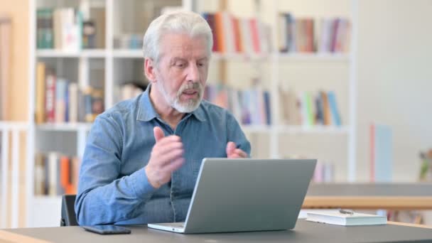 Anciano mayor haciendo videollamada en el ordenador portátil en la biblioteca — Vídeo de stock