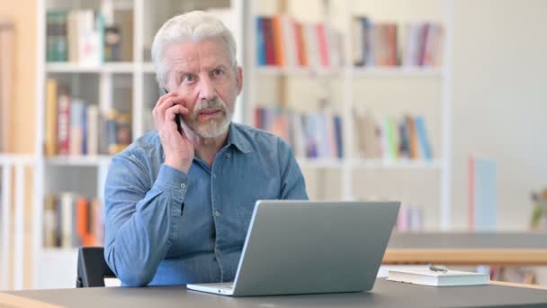 즐겁게 도서관에서 스마트폰으로 통화하는 노인 — 비디오