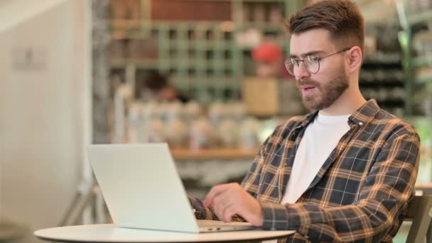 Junger Mann feiert Erfolg auf Laptop im Café — Stockvideo