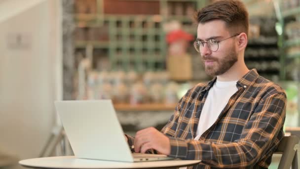 Zieke jonge man met behulp van laptop hoesten in Cafe — Stockvideo