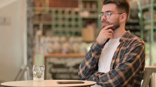 Pensive Młody człowiek siedzi w kawiarni i myślenia — Wideo stockowe