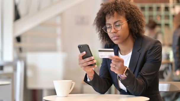 Успешная онлайн-оплата от африканской предпринимательницы на смартфоне в кафе — стоковое видео
