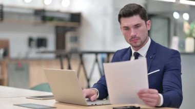 Ofisteki Belgelerle Dizüstü bilgisayarda çalışan İşadamı 