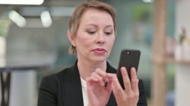 Akıllı telefon kullanan çekici yaşlı iş kadını. 