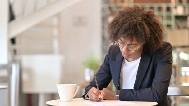 Pensive African Businesswoman Pisanie na papierze w Cafe — Wideo stockowe