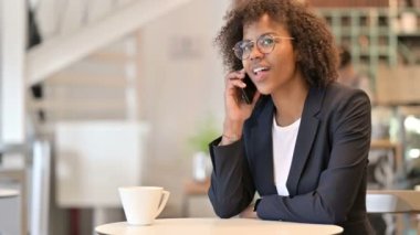 Neşeli Afrikalı İş kadını Kafe 'de Smartphone' dan konuşuyor 