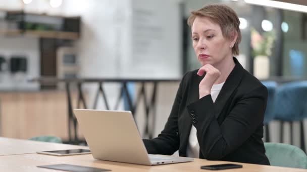 Vieille femme d'affaires Penser et travailler sur ordinateur portable dans le bureau — Video