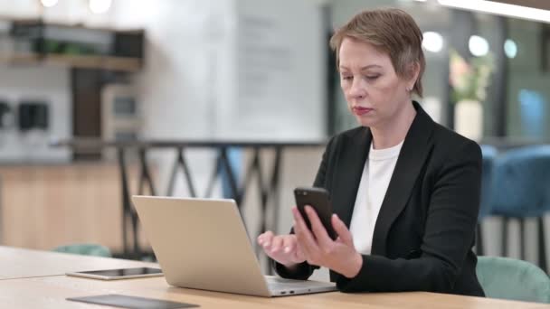 Attraktive alte Geschäftsfrau mit Smartphone und Laptop — Stockvideo